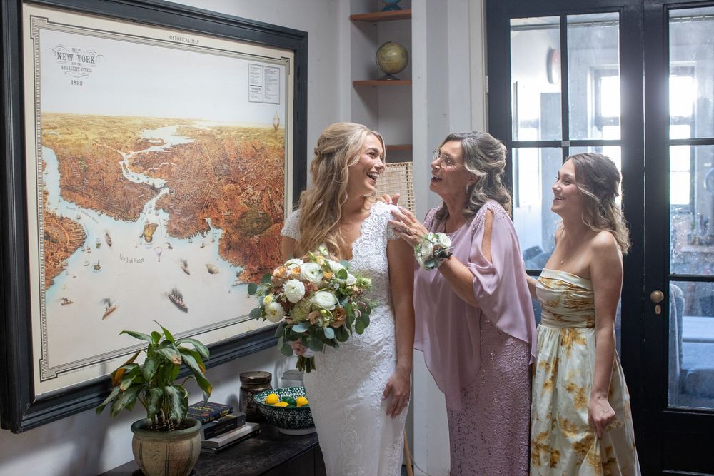Bride laughing with family members while holding white bouquet in front of vintage New York map.
