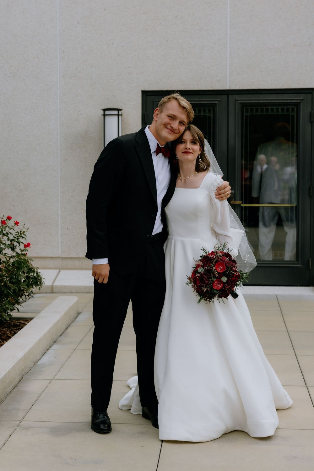 Close-up shots of a bride's white wedding dress and groom's black suit shoes on a light colored floor.