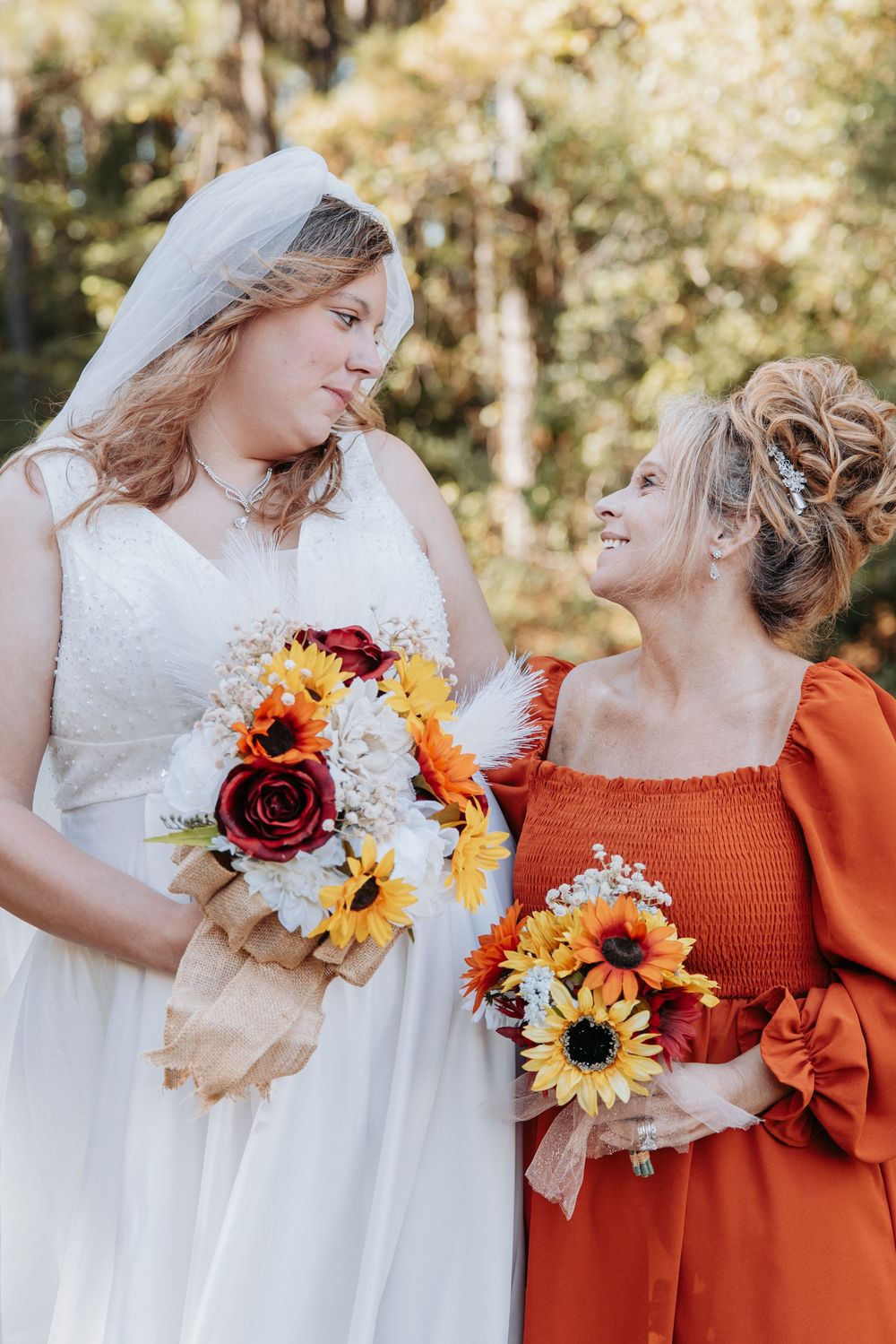 Wedding party detail shot showing orange dresses and fall-themed floral bouquets.