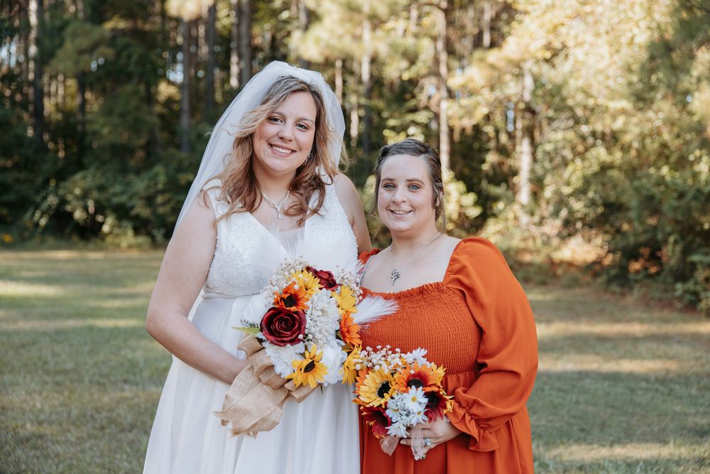 Bridal party in orange and white dresses posing together outdoors.