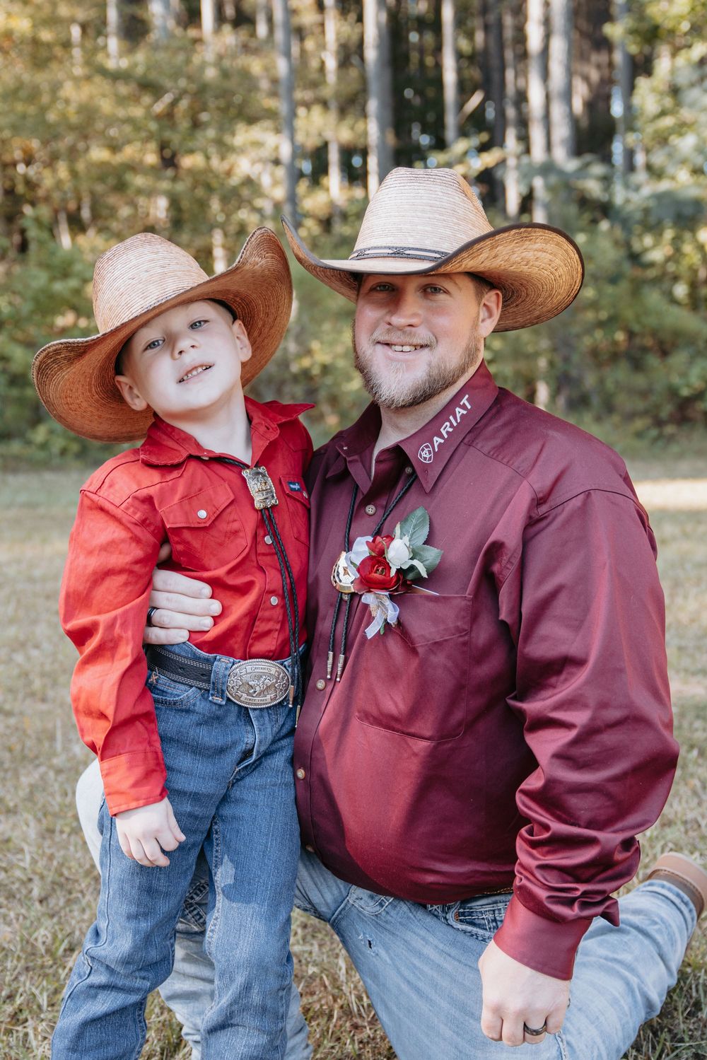 Family wearing coordinated western outfits with burgundy shirts and cowboy hats in an outdoor setting.