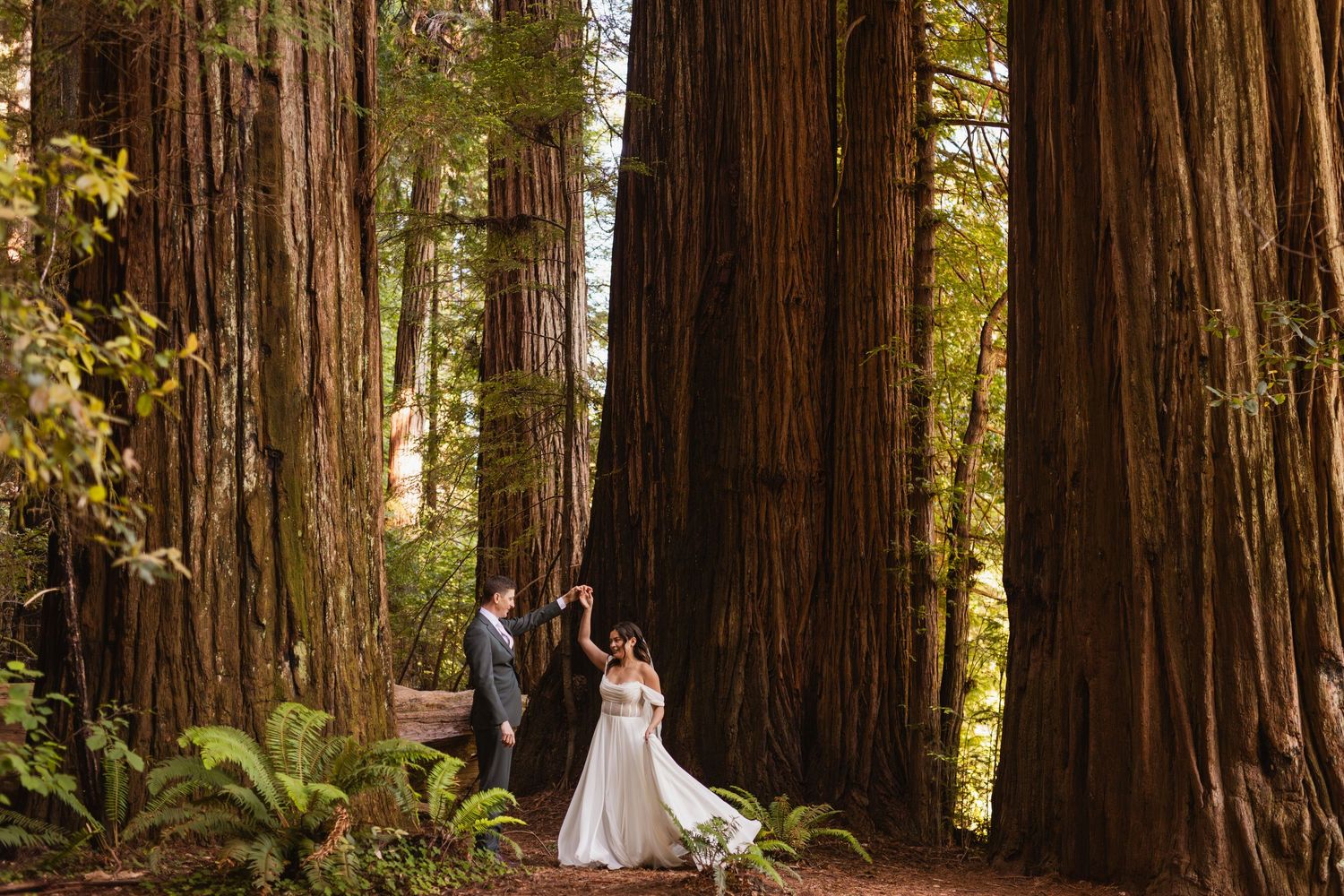Bride and groom exchange vows among towering redwood trees in a forest wedding.