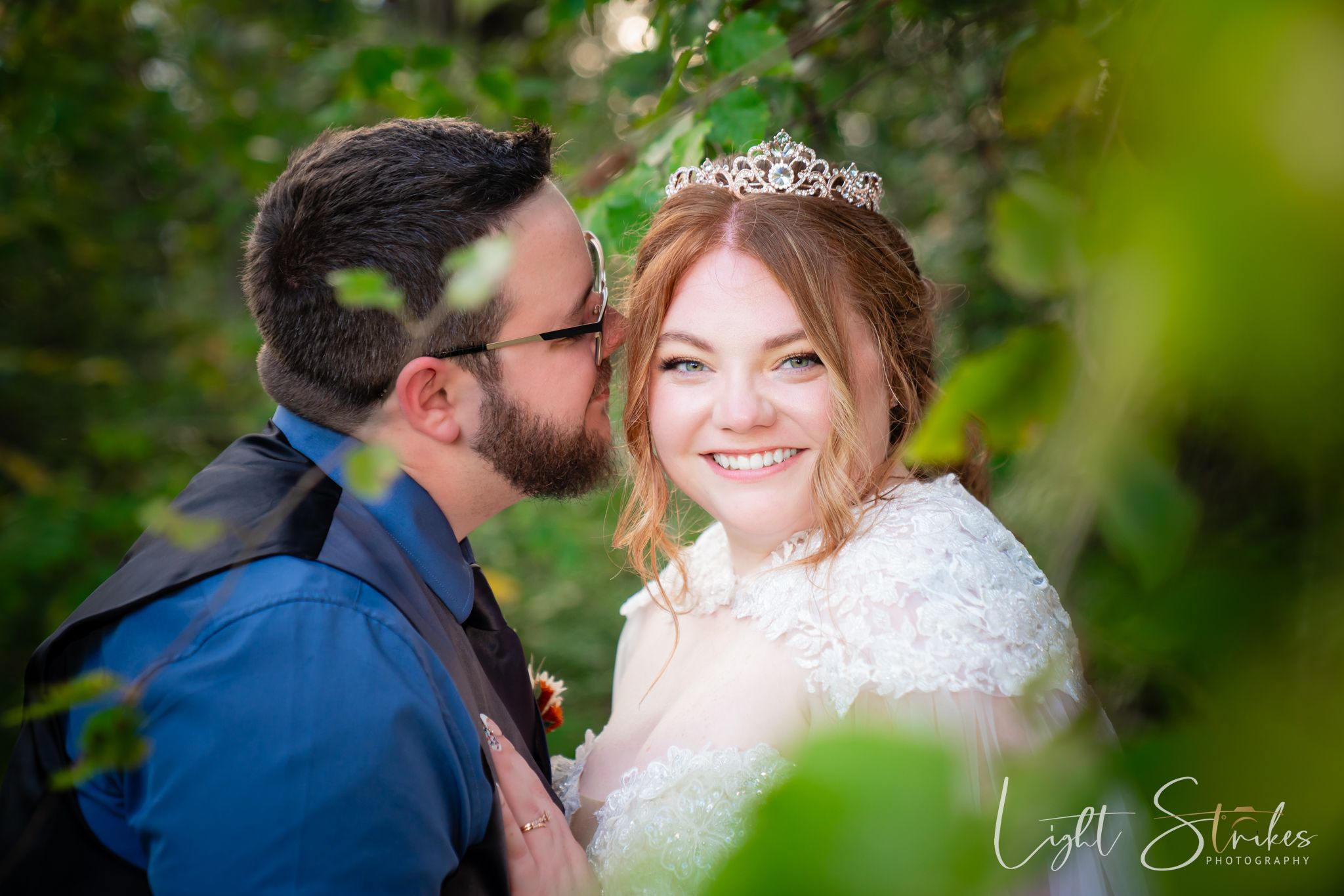 A happy couple shares a tender moment in their wedding attire among green foliage at rustic wedding at North Carolina farm.