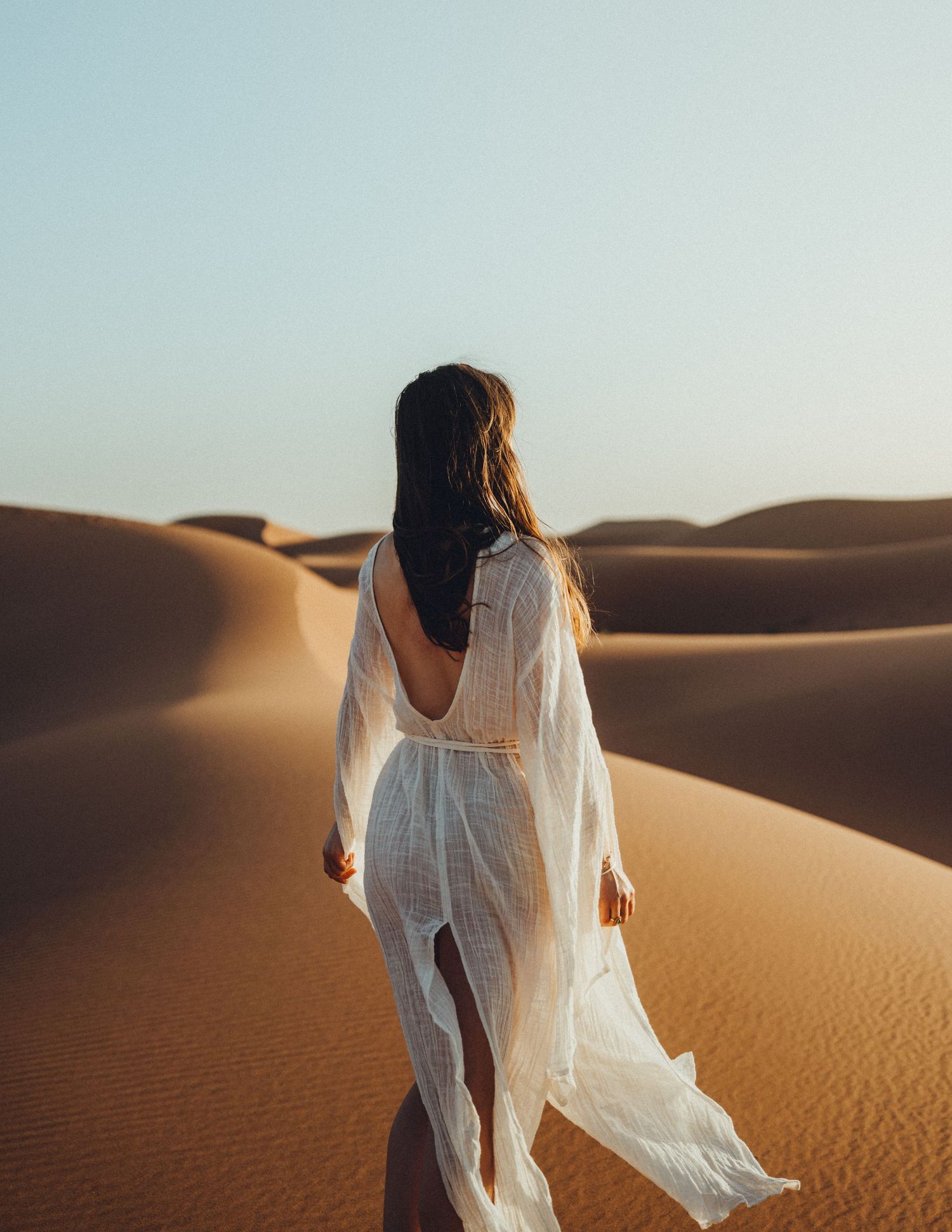 Desert fashion photoshoot featuring a woman with a flowing dress, capturing dynamic movement and brand storytelling.