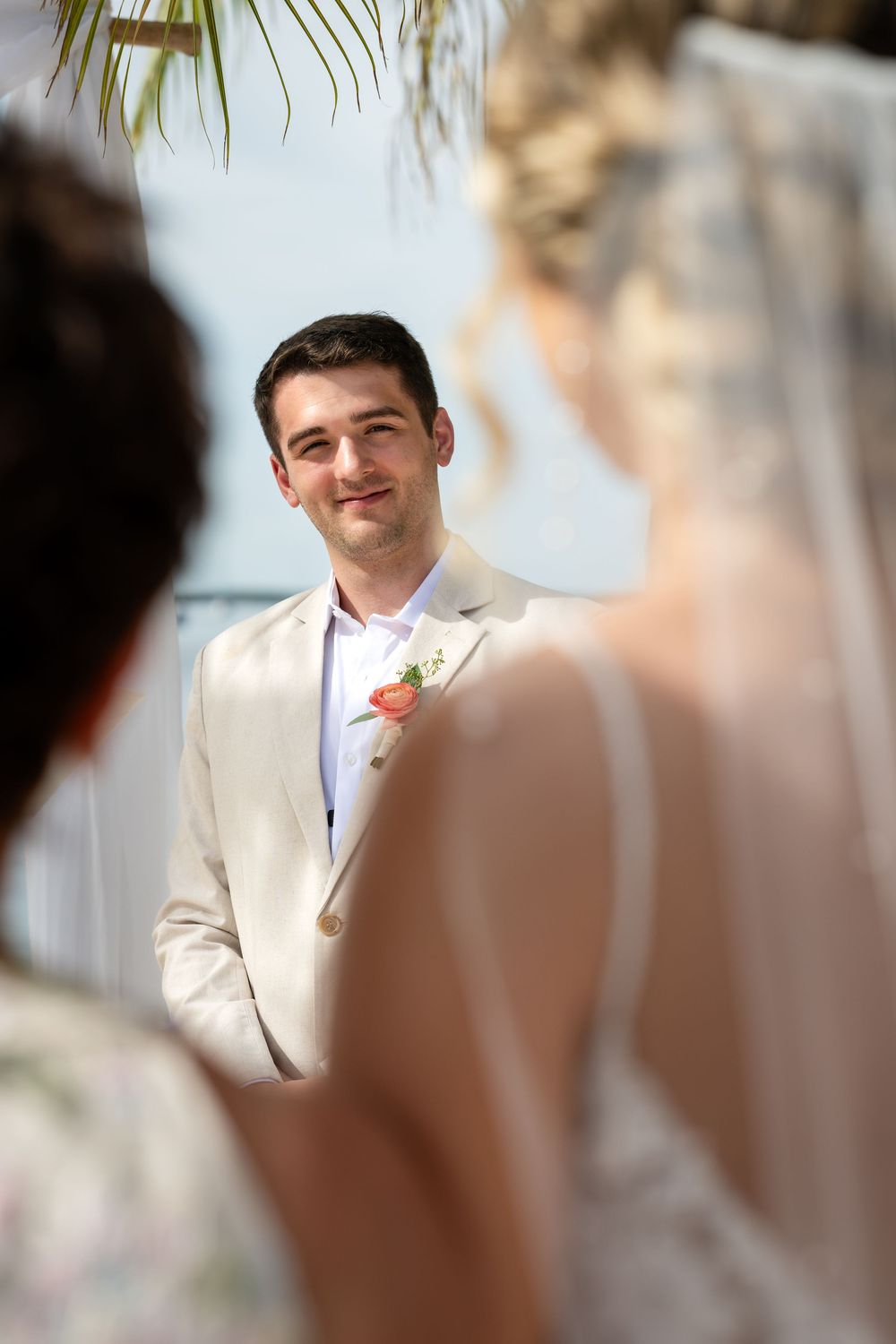 Wedding ceremony moments captured in soft focus with palm fronds in background.