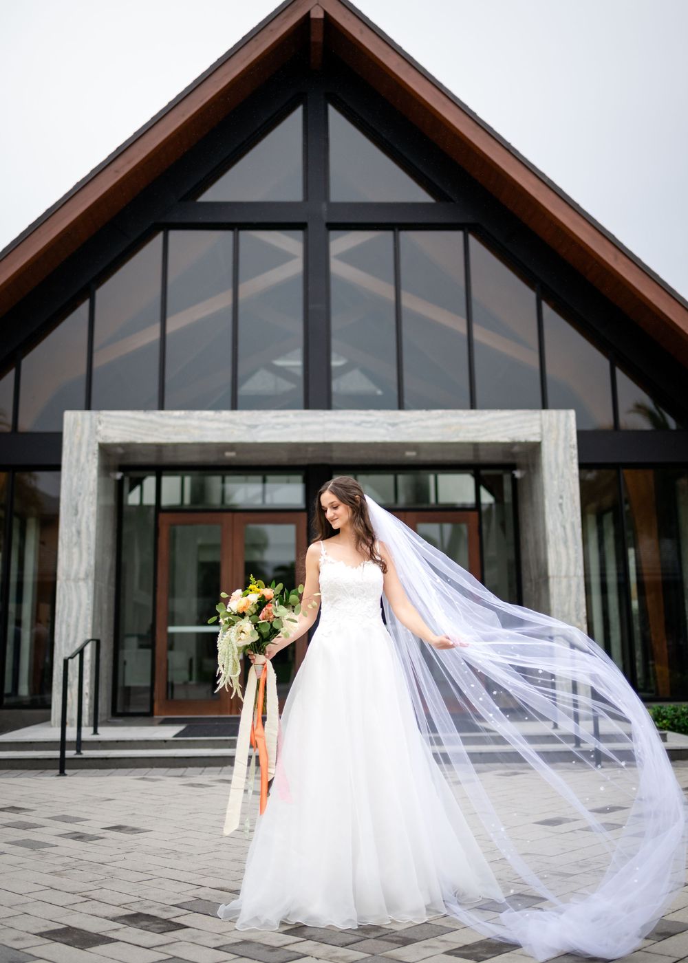 Modern wedding venue exterior with flowing veil and architectural details.