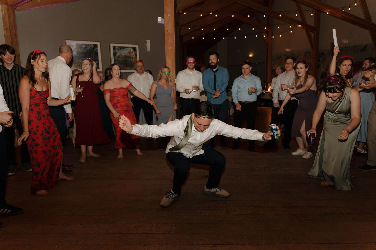 Wedding guests dance and celebrate on a dimly lit dance floor during an evening reception party.