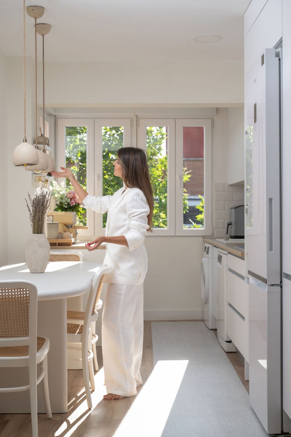 Bright modern kitchen interior with white cabinets, pendant lights and a breakfast bar bathed in natural sunlight.