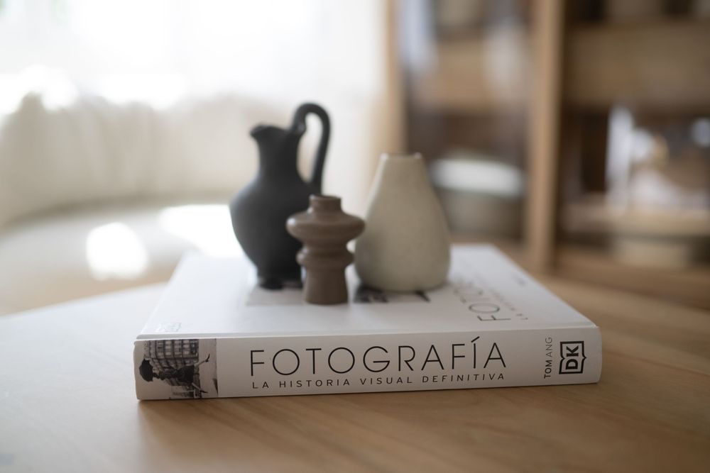 Soft focus close-up of white ceramic objects on a wooden table with photography branding.