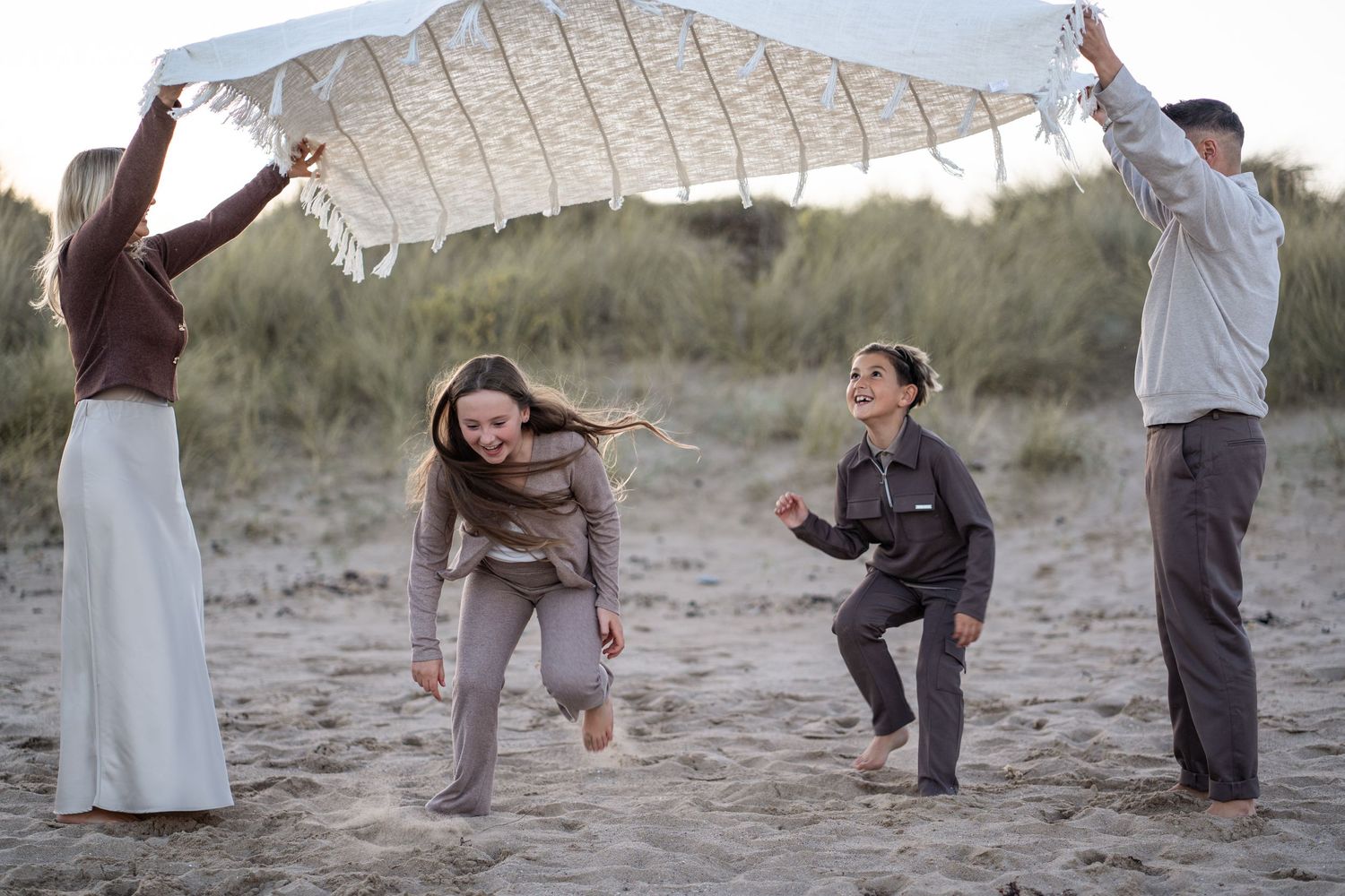 A sequence of dance moves performed by people on a sandy beach at dusk.