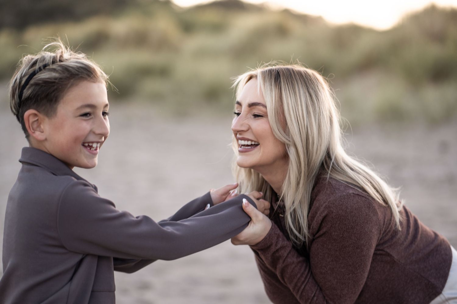 Two people share joyful moments together outdoors during a photoshoot at sunset.