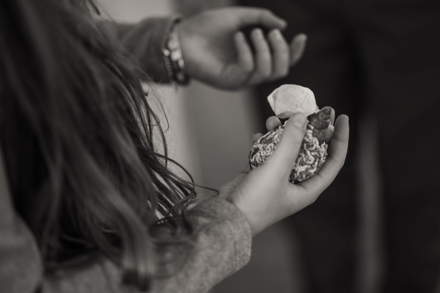 Close-up black and white photo of hands wearing jewelry and rings with dramatic lighting.