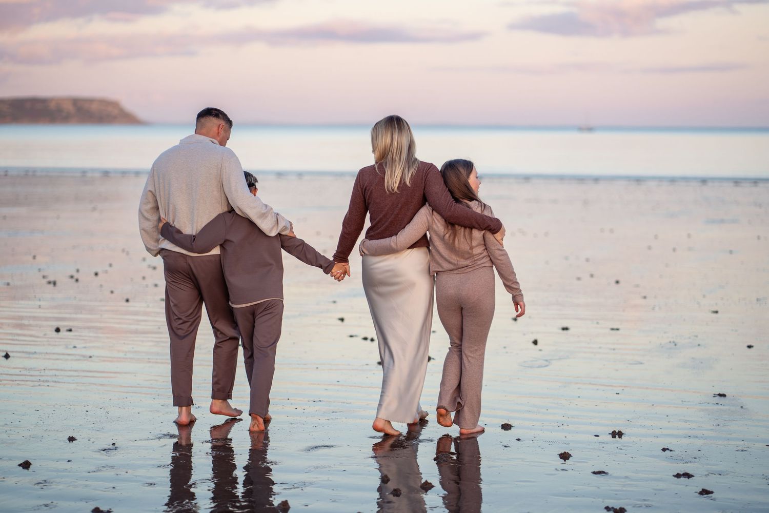 People walking along a sandy beach at sunset collecting seashells and enjoying the peaceful ocean view.