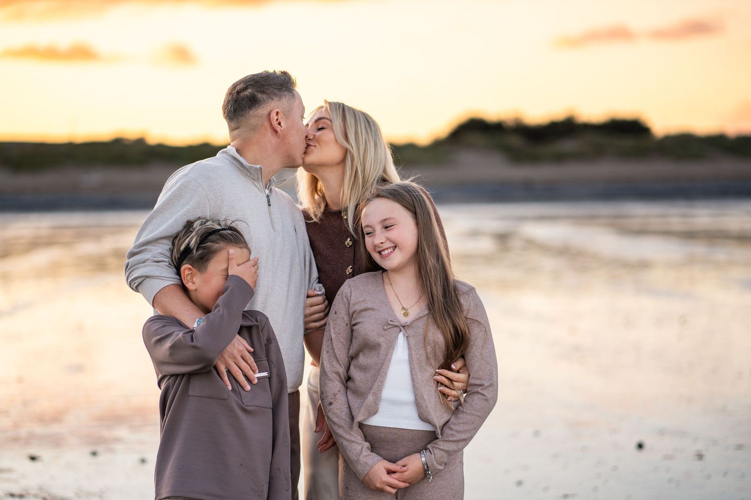 Couple embraces on beach during golden sunset creating romantic silhouettes in multiple candid moments.