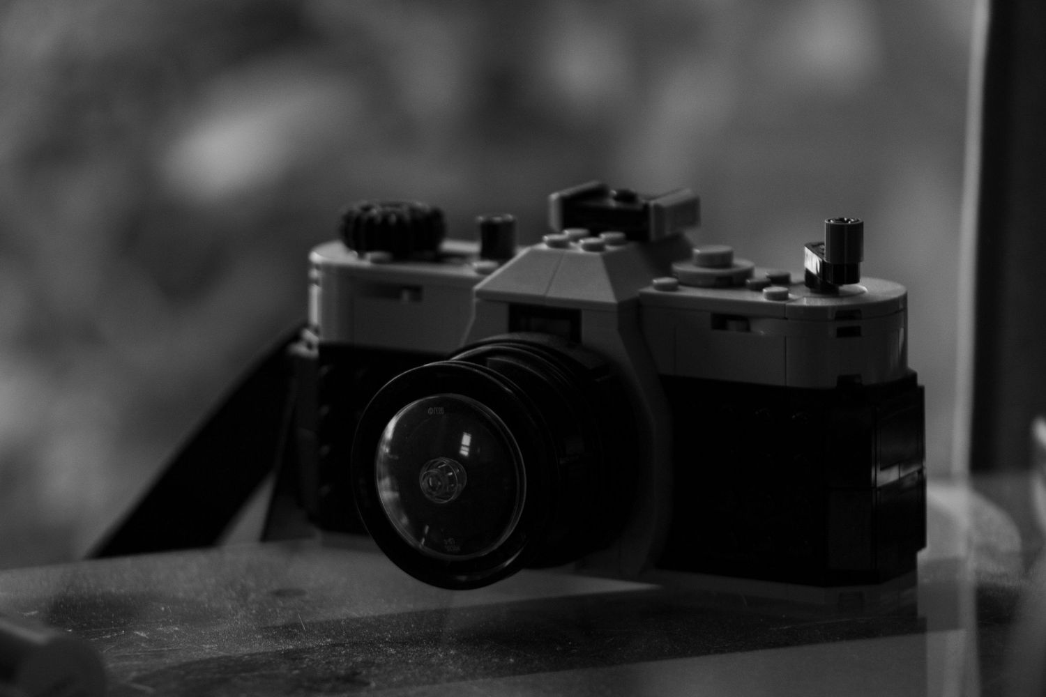 Black and white close-up of a vintage film camera resting on a surface.