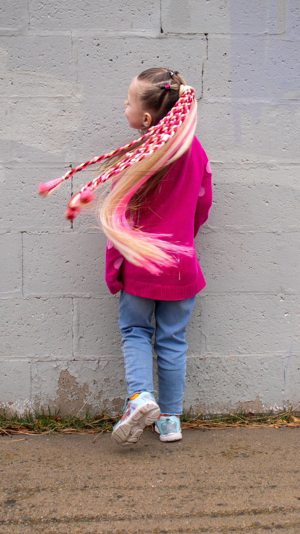 Young girl with long braided hair wearing a pink jacket during a lifestyle hair branding session