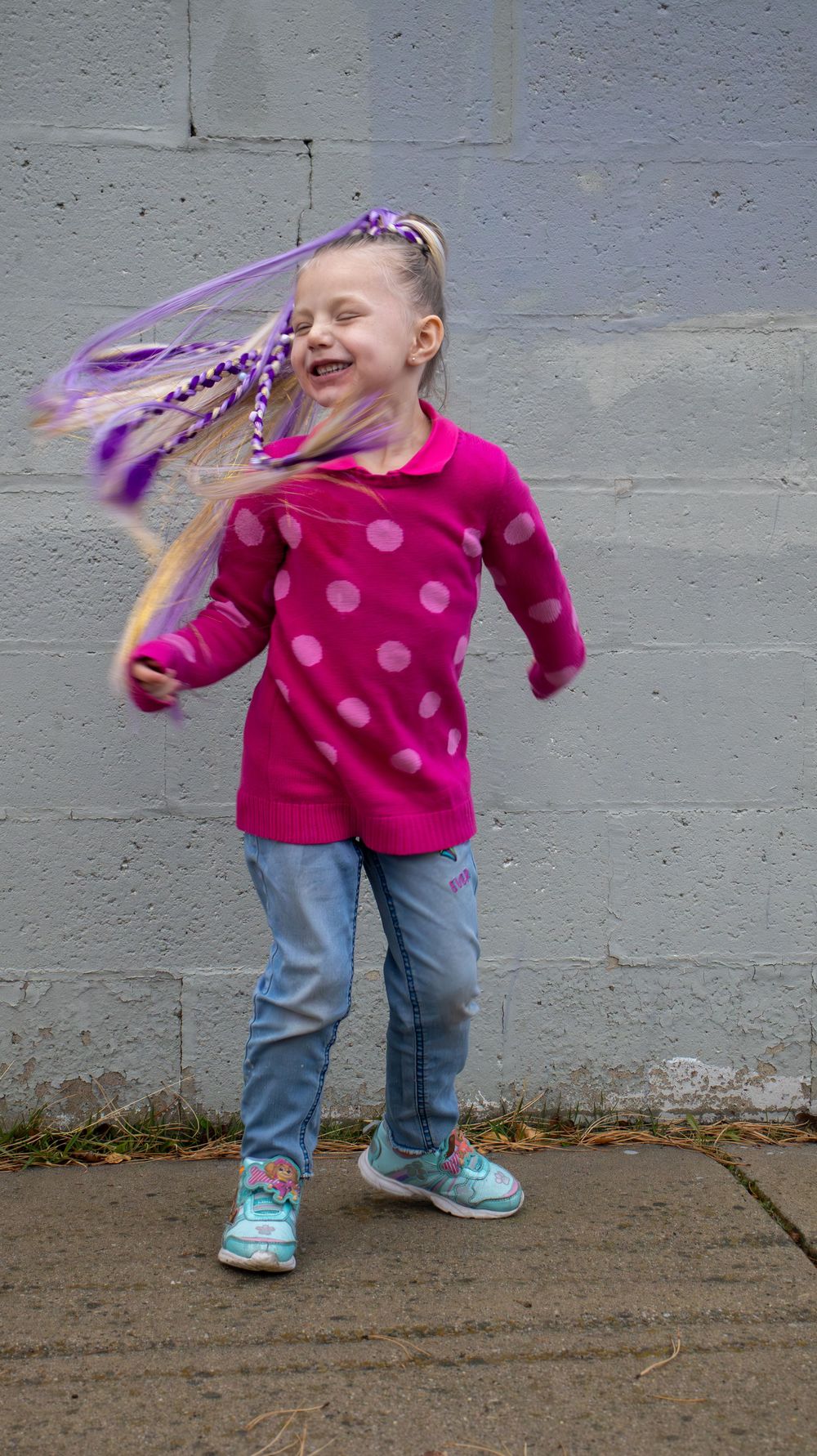 Young girl with long braided hair wearing a pink jacket during a lifestyle hair branding session