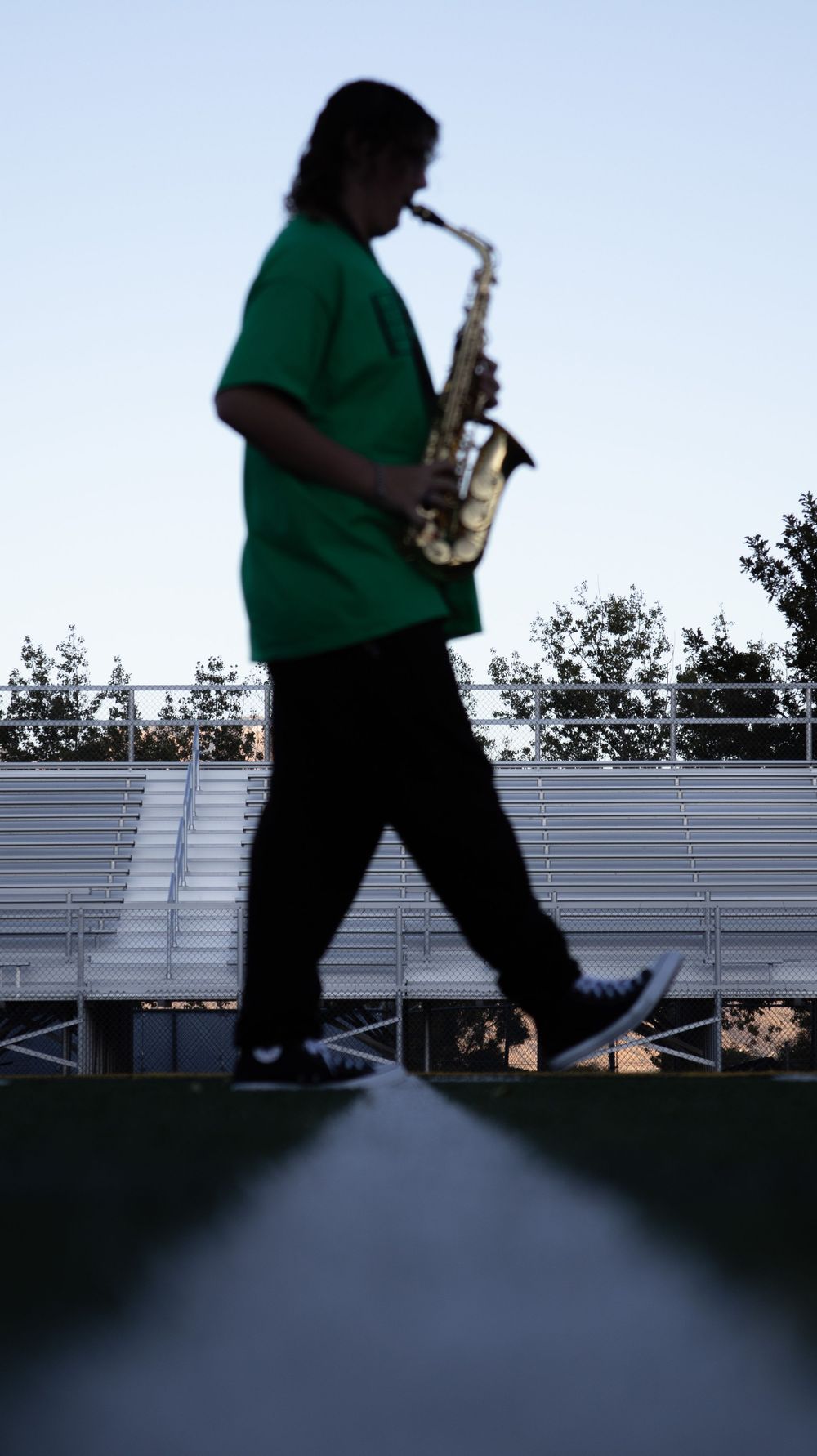 Teen boy walking with saxophone during an outdoor senior photo session