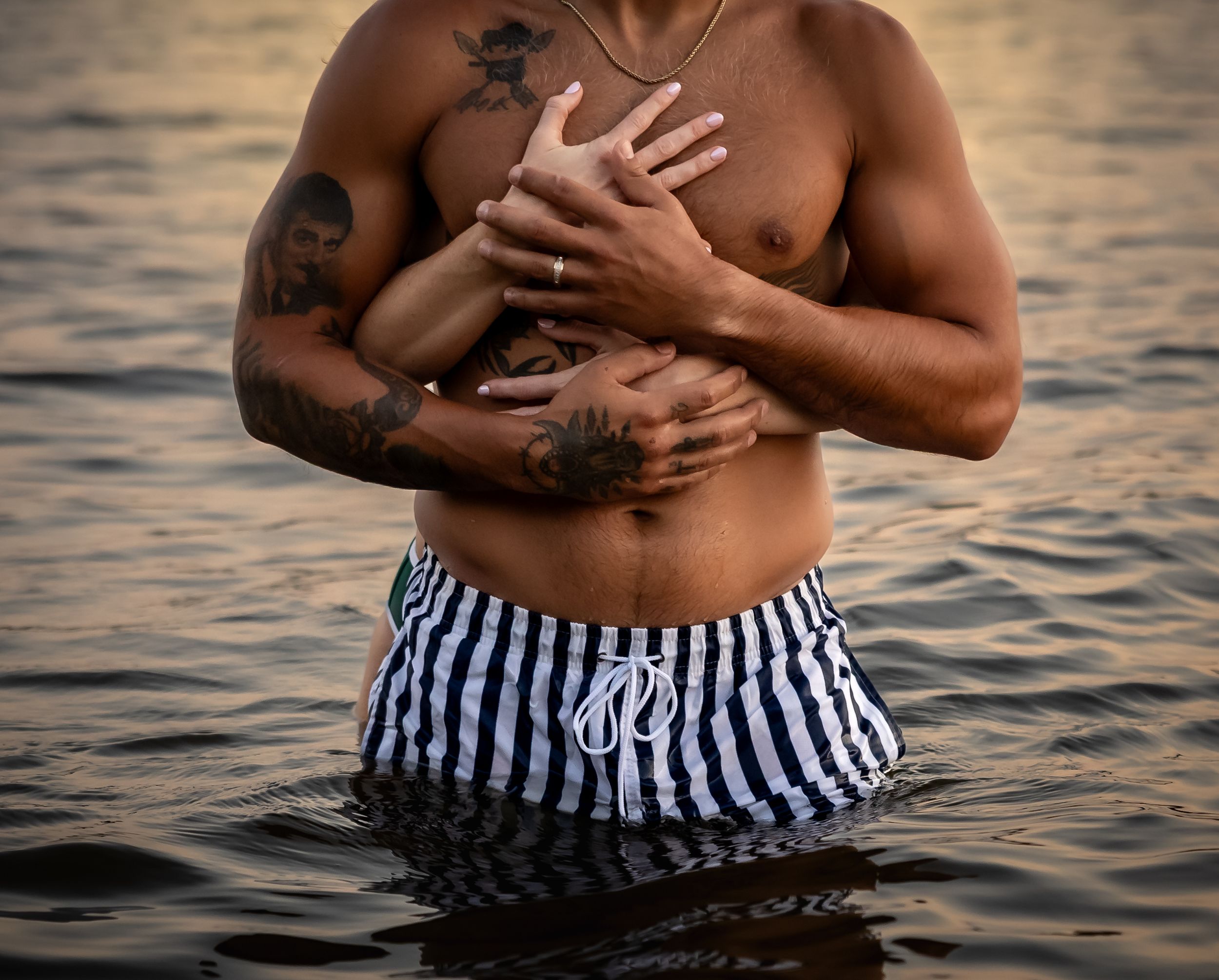 Intimate couple moment captured in water during golden hour sunset.