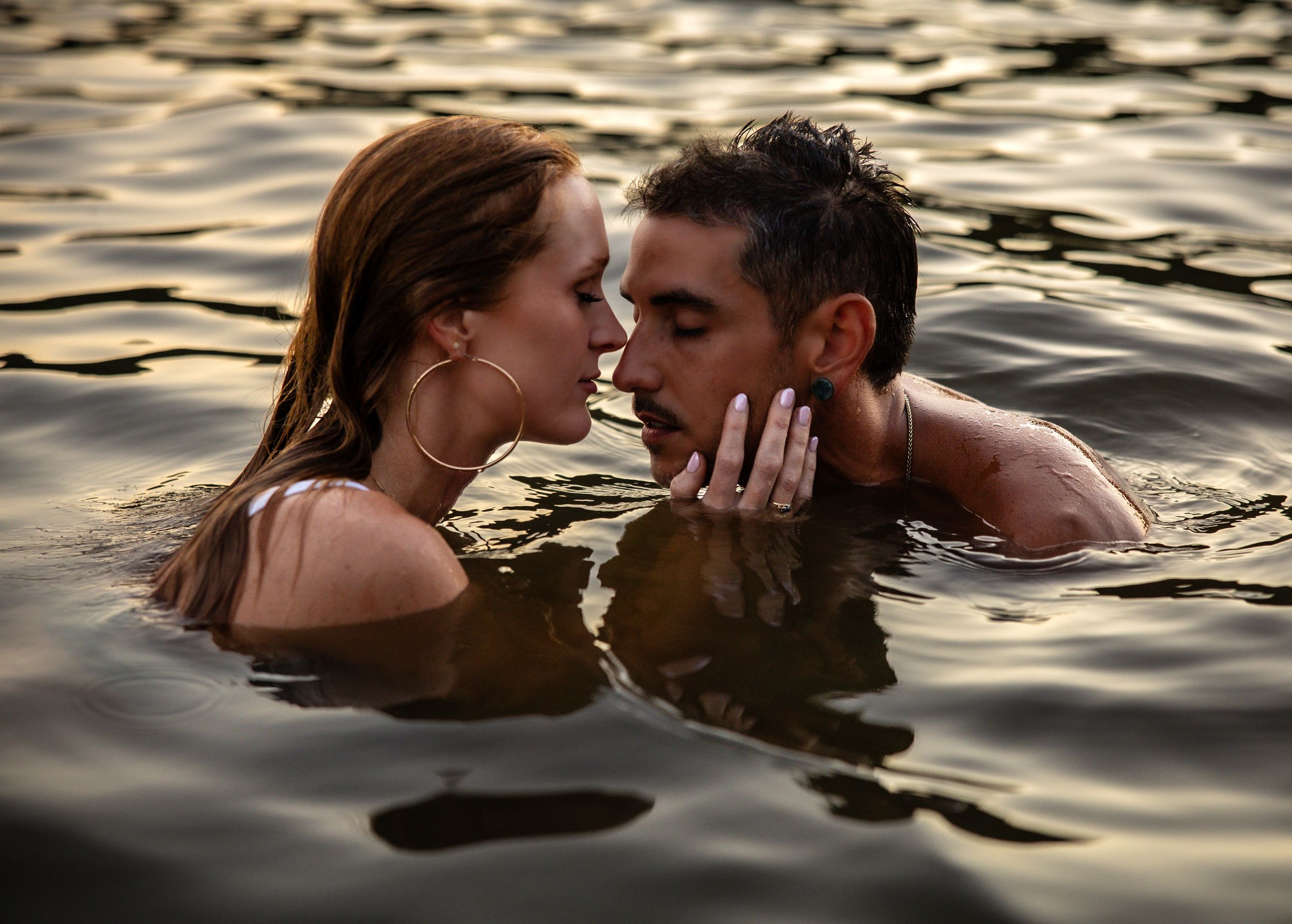 Intimate couple photography in golden water with dramatic sunset lighting.