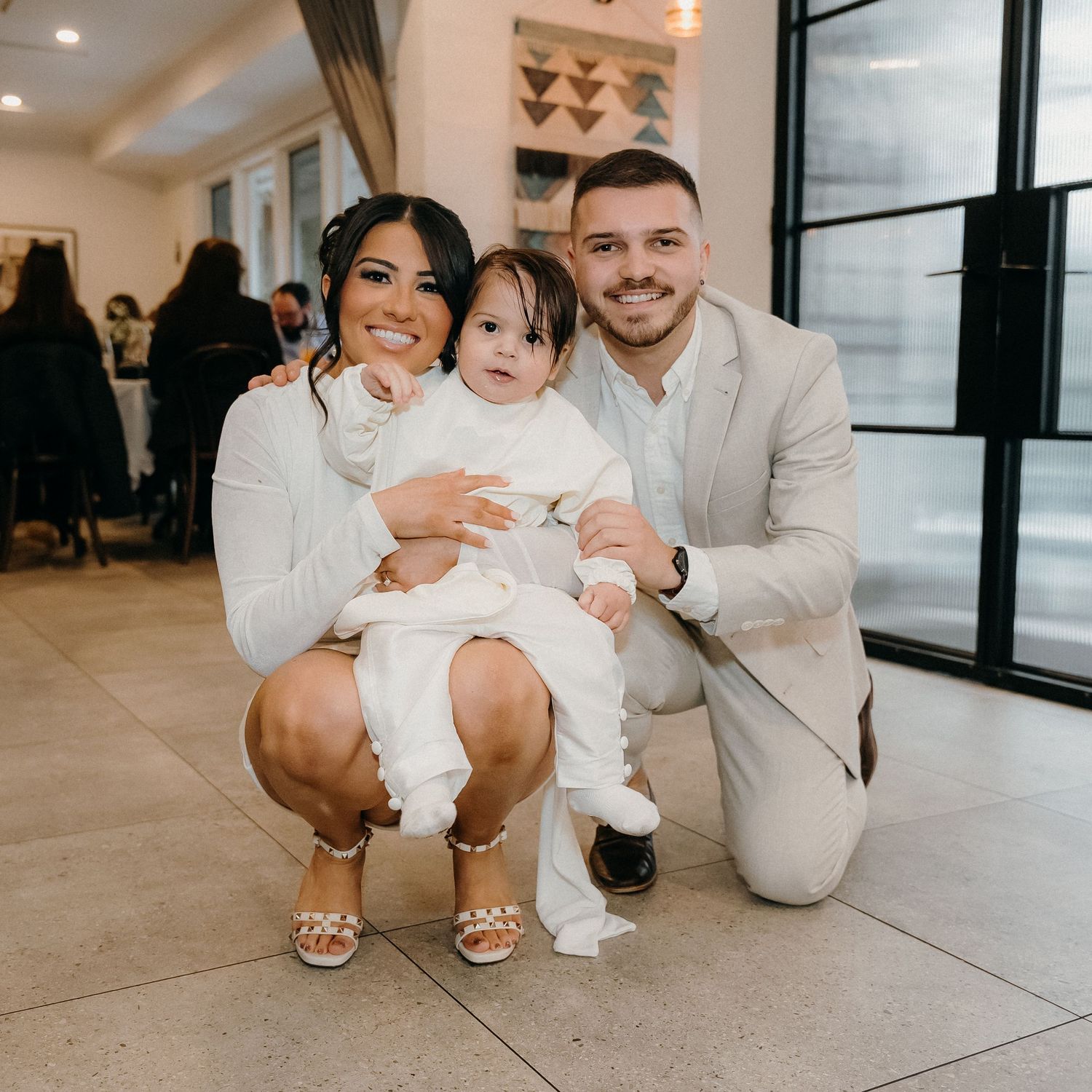 Family sitting on floor in modern interior wearing coordinated white and beige outfits for a photoshoot.
