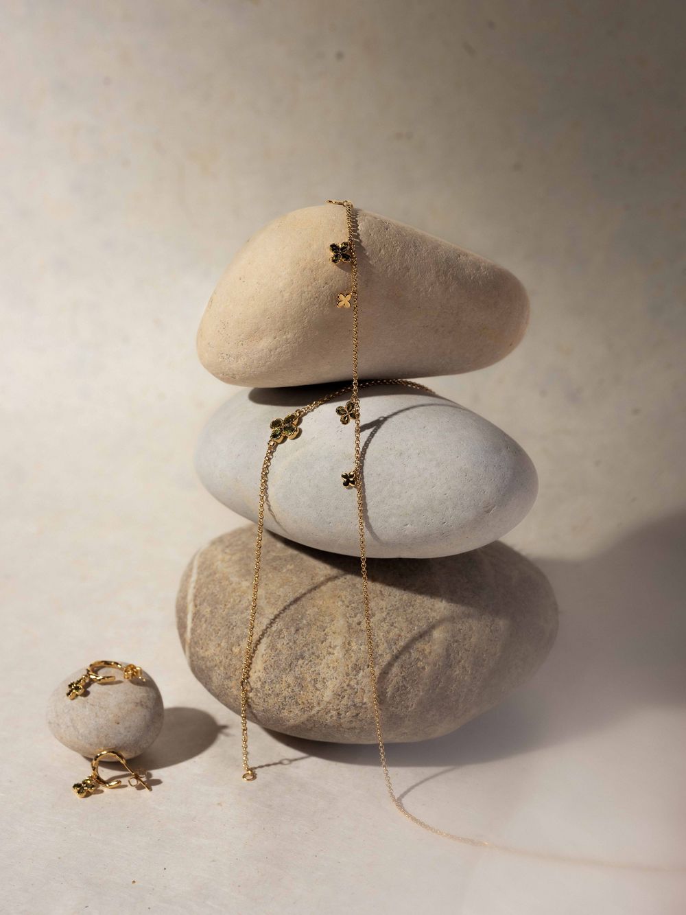 Small gecko lizard perches on smooth river stones against neutral background in artistic nature photography series.