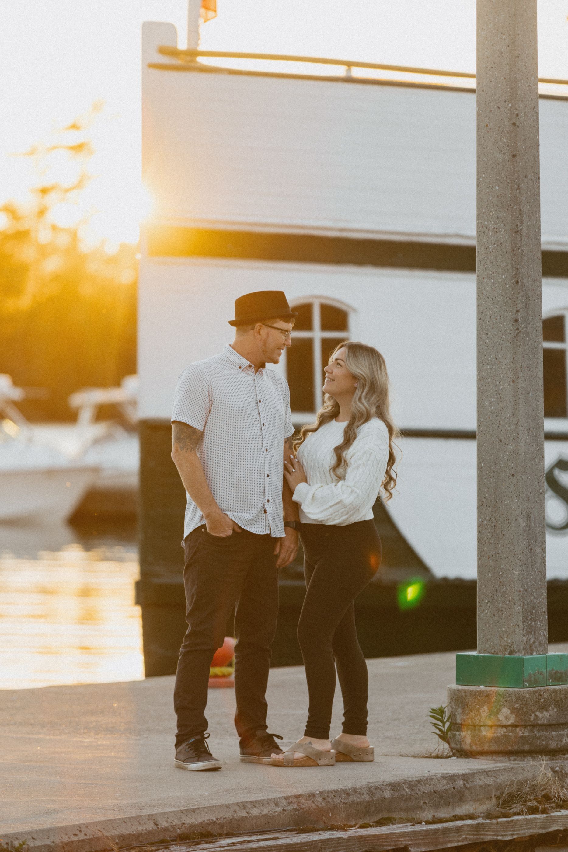 Silhouettes of a couple walking along the waterfront at golden hour.