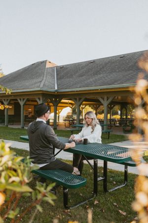 Two people share an intimate moment on a green bench outside a building with yellow lighting.