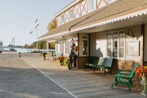 Long view of a waterfront boardwalk with green benches and white buildings.