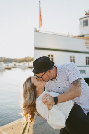 A romantic moment shared between two people against a waterfront backdrop.