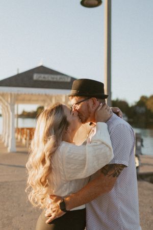 A tender embrace captured in golden sunlight near the waterfront.