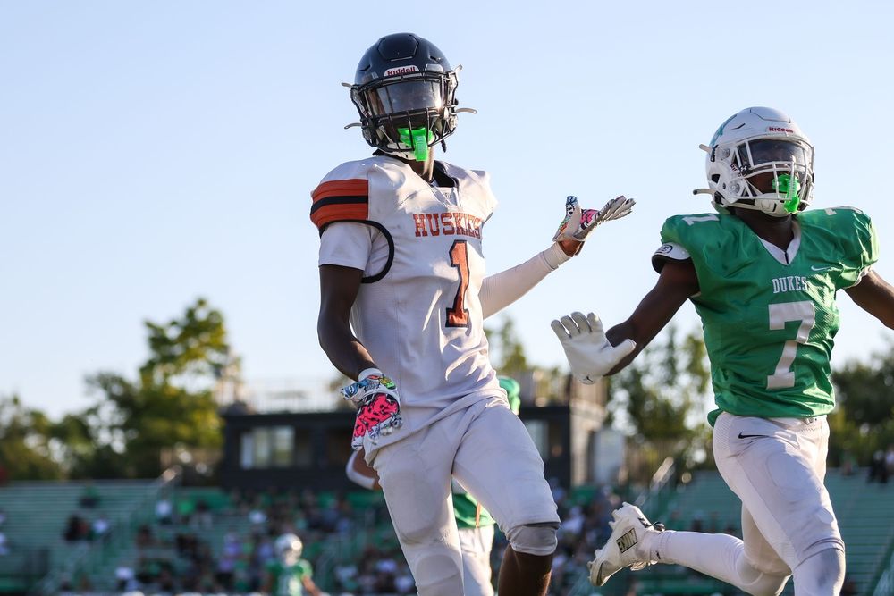 Football players in green and white uniforms compete during an intense game on the field.