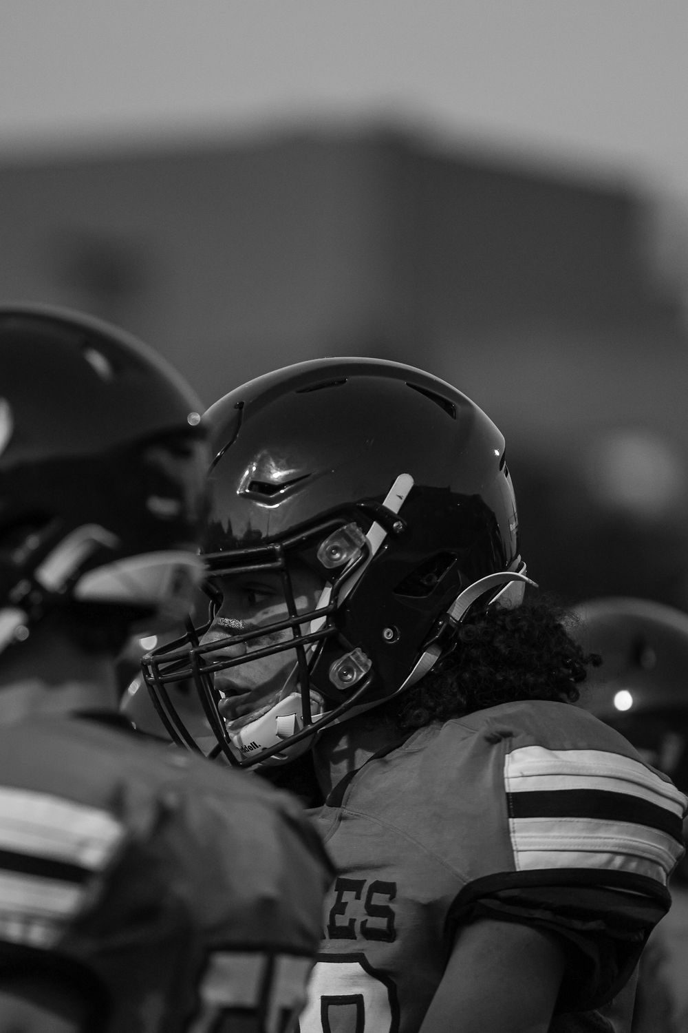 Row of black football helmets lined up on the sideline during a game.