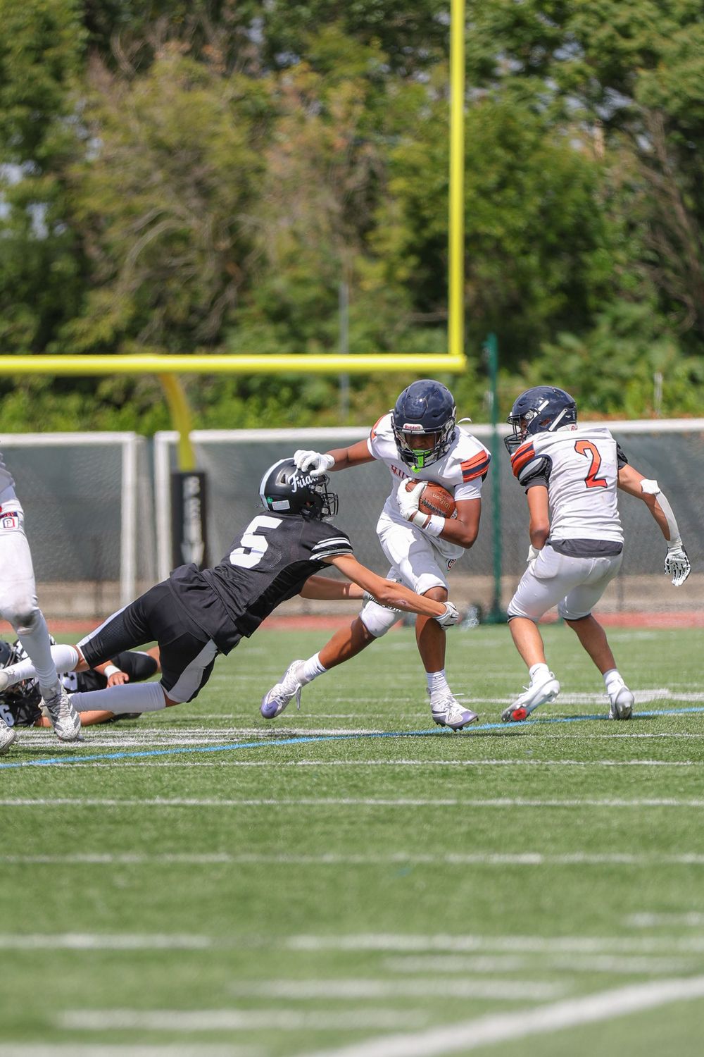 Multiple football players diving and tackling during an intense game play sequence.
