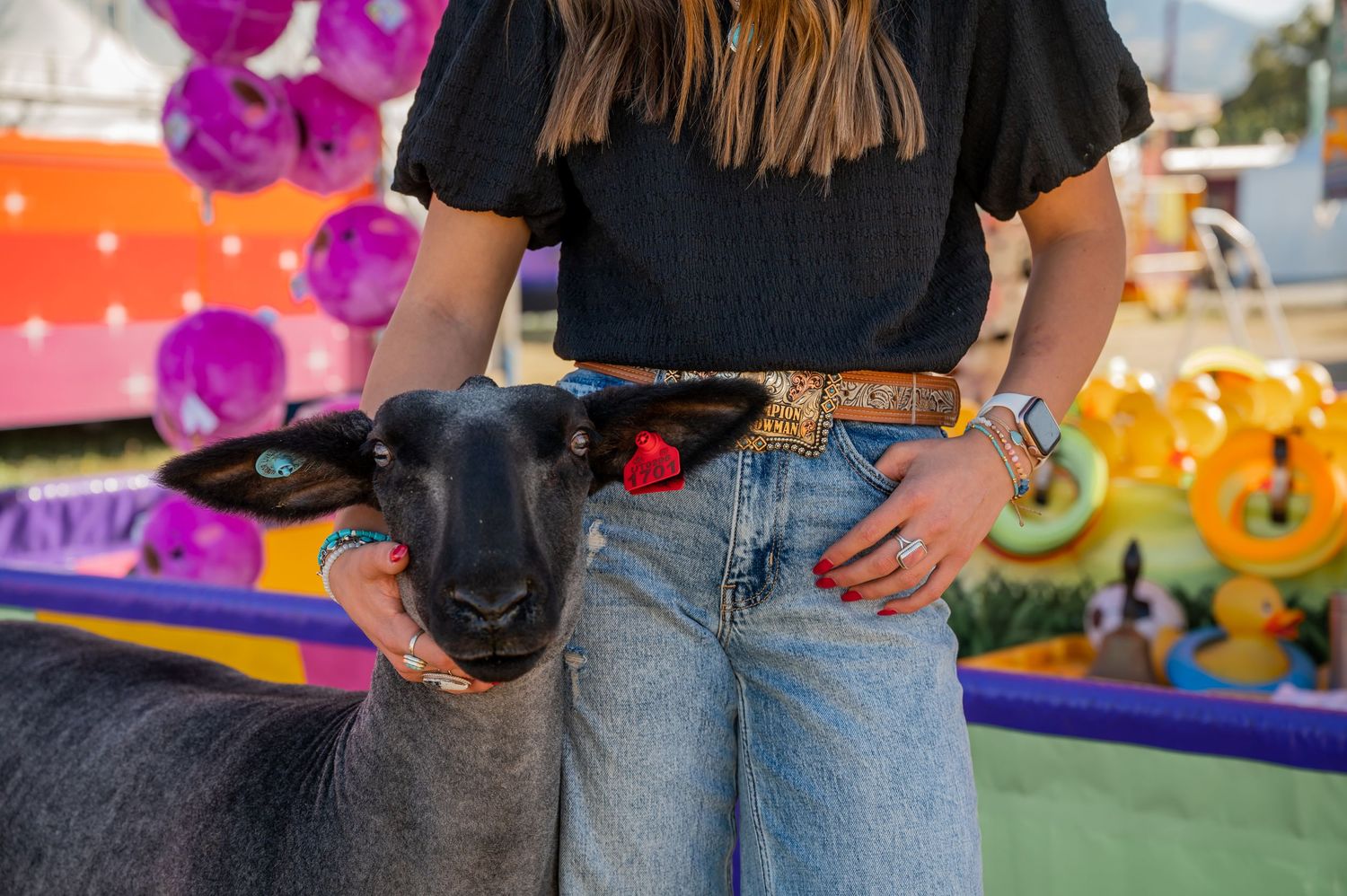 Casual western outfit with jeans and belt against colorful carnival background.