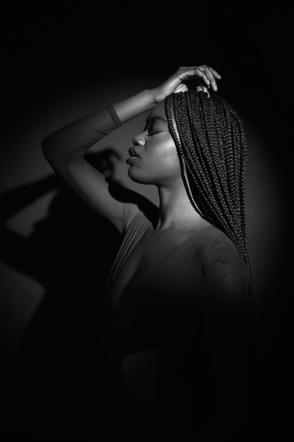 Artistic black and white portrait series showing dramatic shadows and braided hair in moody lighting.