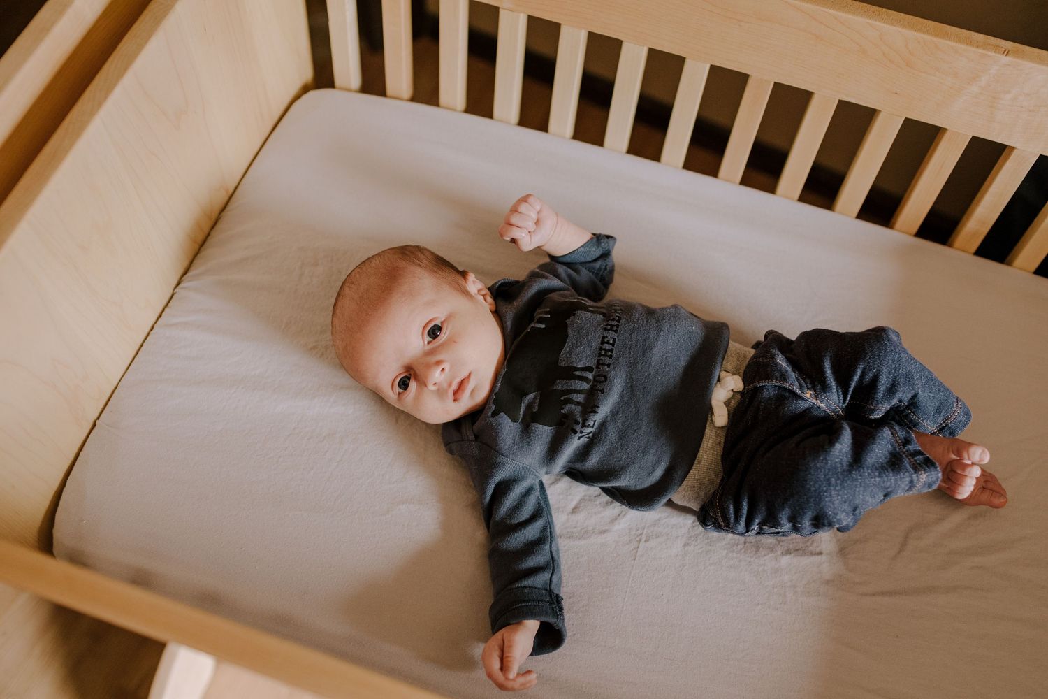 Baby lying on beige crib mattress in various poses.