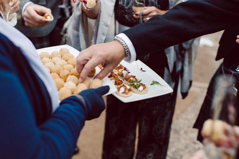 Hands reaching for popcorn samples being served on small paper plates at a food tasting event.
