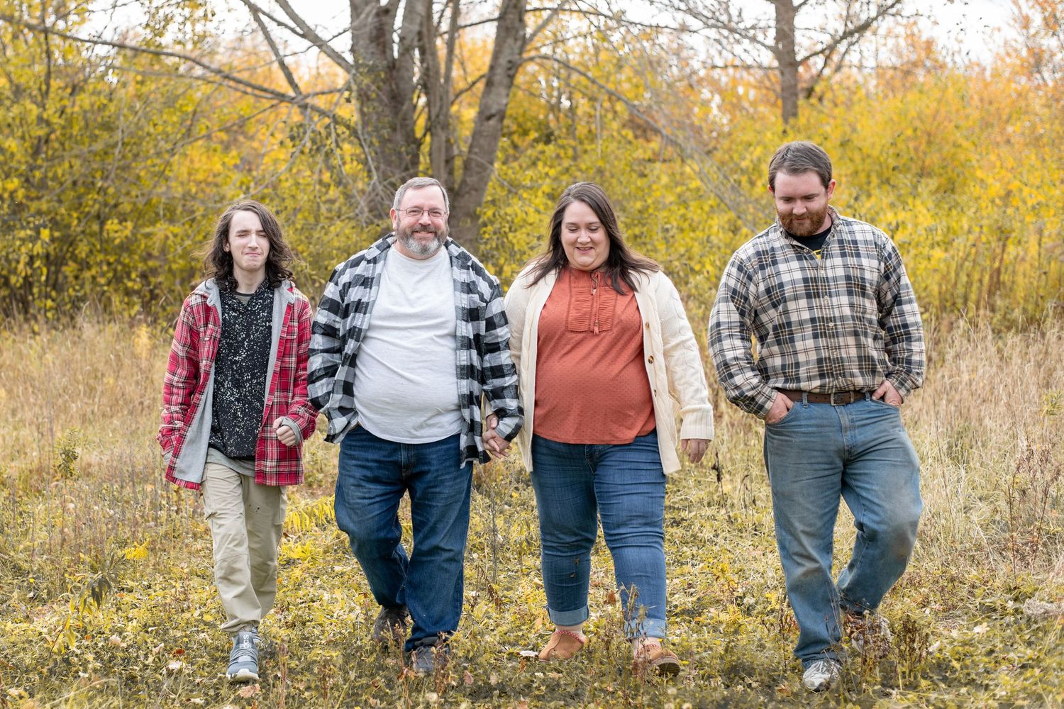 Group portrait of four people standing together in a field at dusk.