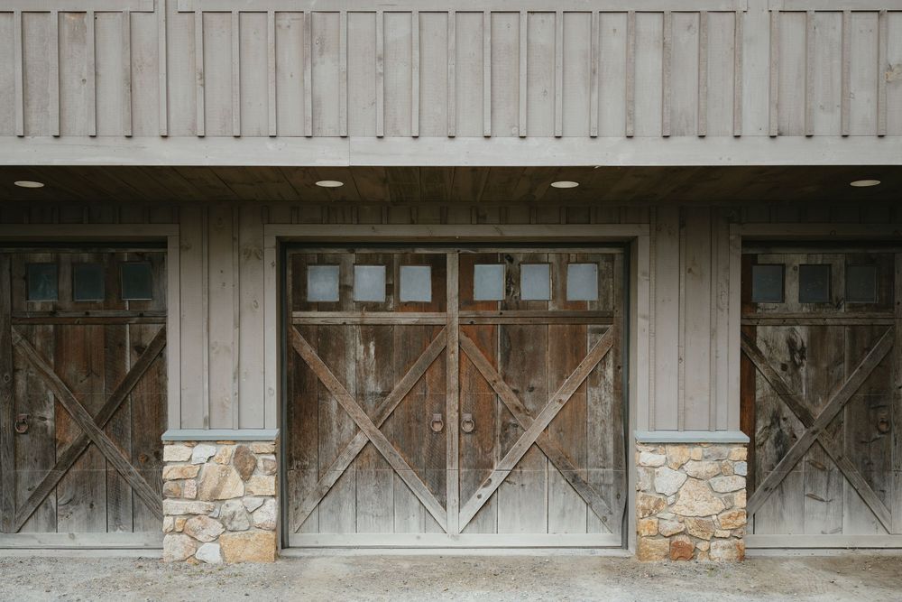 A rustic wooden garage door with diagonal patterns and stone accents adorns the exterior of a building.