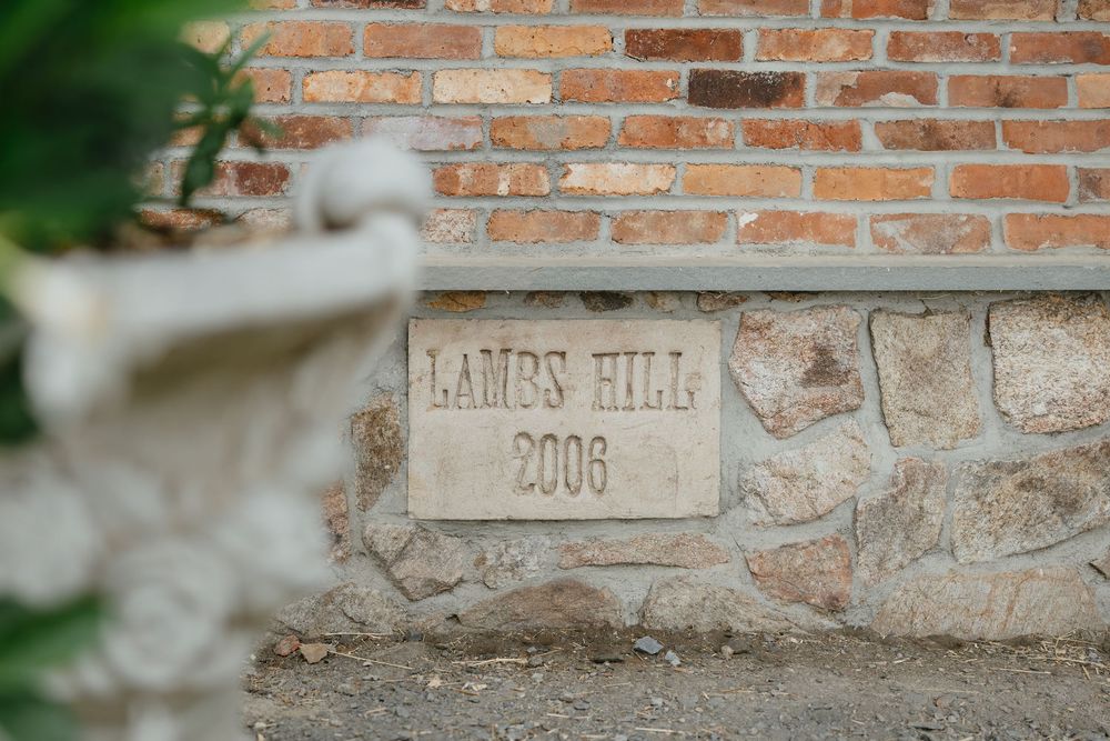 Carved stone wall with text 'James Hill' and '2008' etched into weathered blocks.