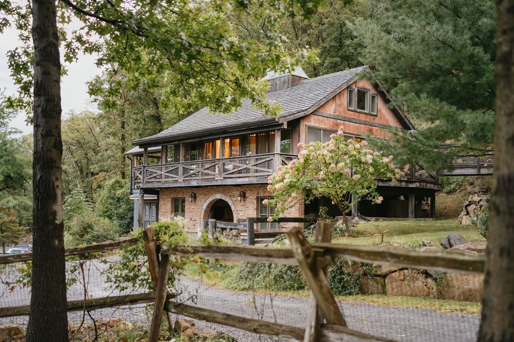 Rustic log cabin venue nestled in a wooded area with stone pathways and natural landscaping.