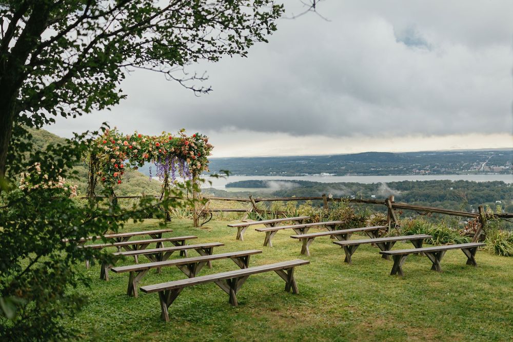 Panoramic view of wooden picnic tables overlooking a scenic mountain valley on a cloudy day.