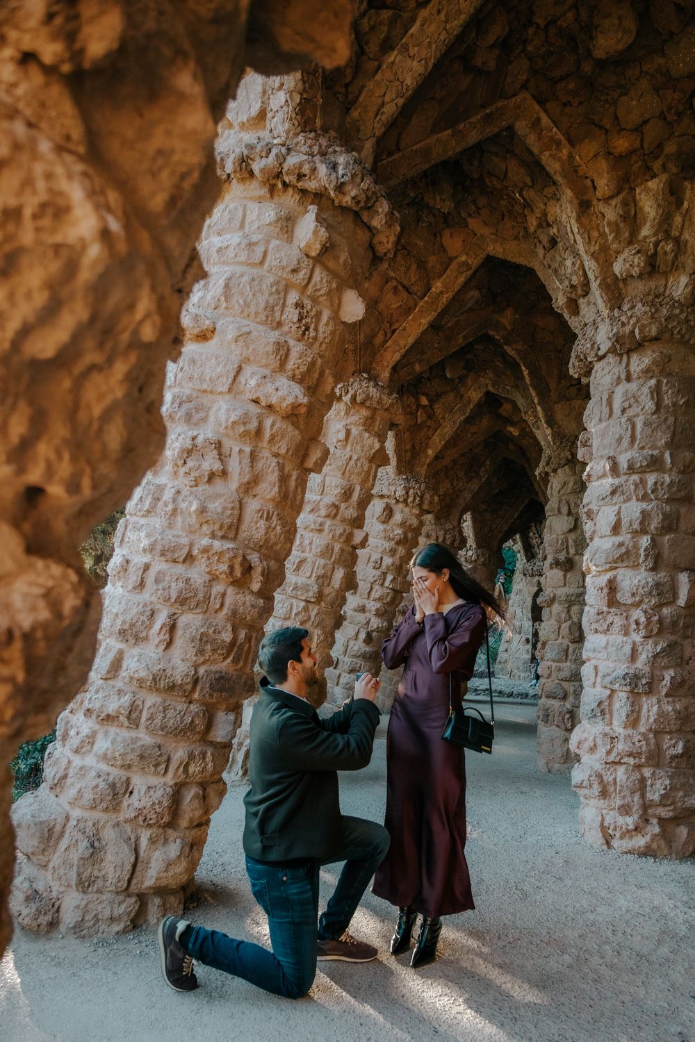 Couple embracing under the stone arches of Park Güell
