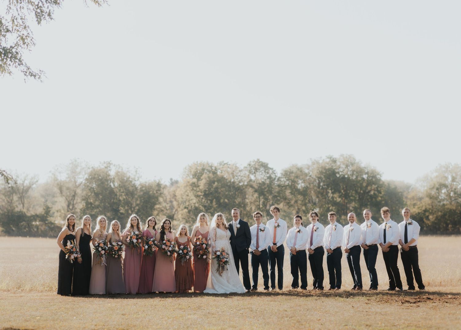 Bride in lace gown with bridal party posing for outdoor wedding photo by destination wedding photographer in Wisconsin.