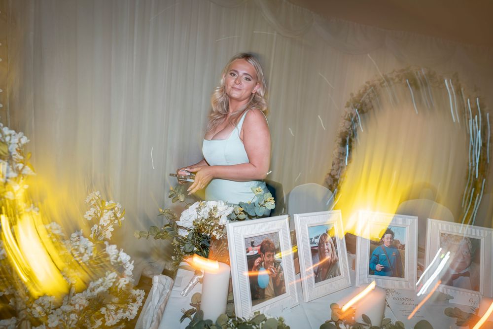 Wedding reception decor with illuminated display and floral arrangements.