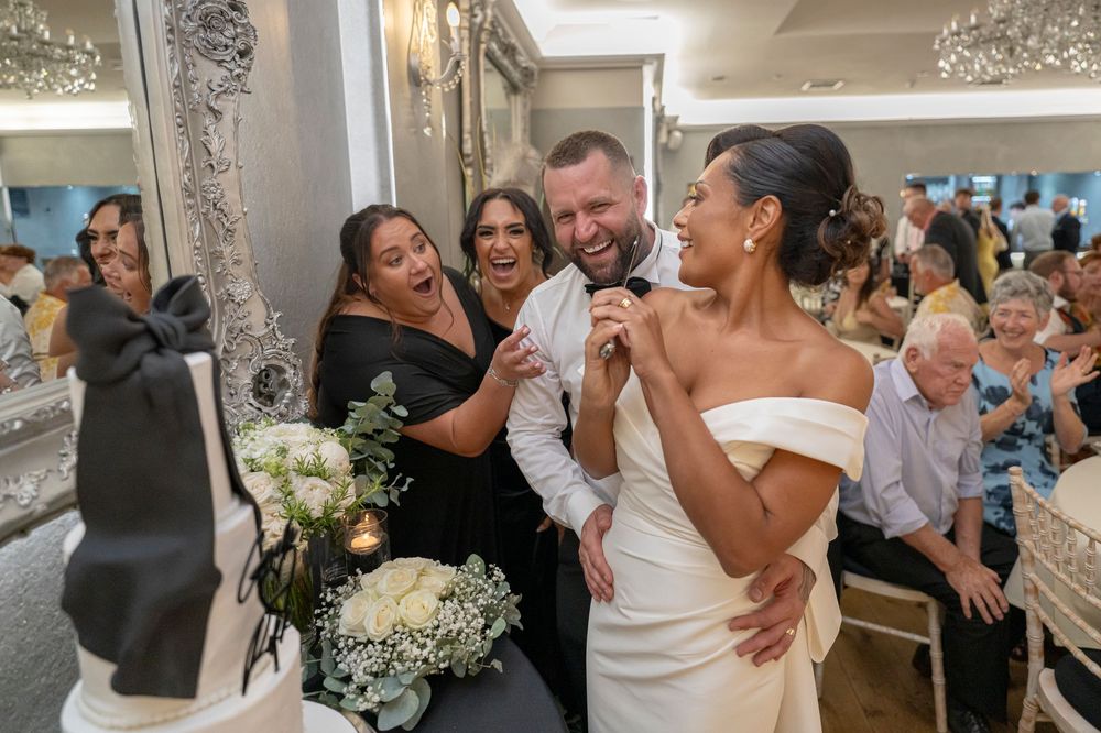 Wedding celebration candid moments with guests hugging and dancing in an elegant venue.