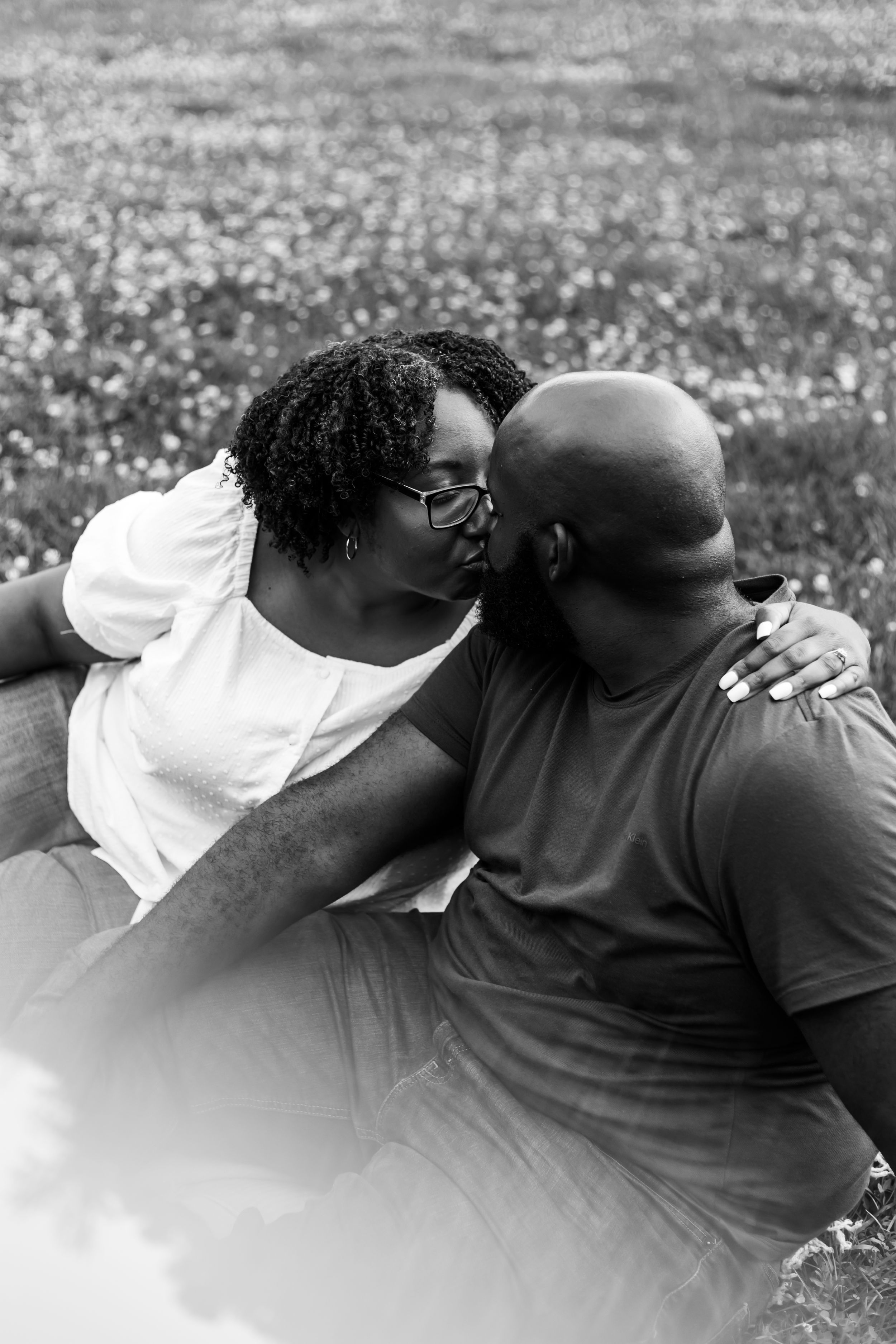 A series of intimate black and white photographs showing a couple embracing on grass in a park.