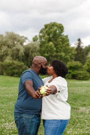 A couple shares a tender moment together in a sunny meadow with white wildflowers and green grass.