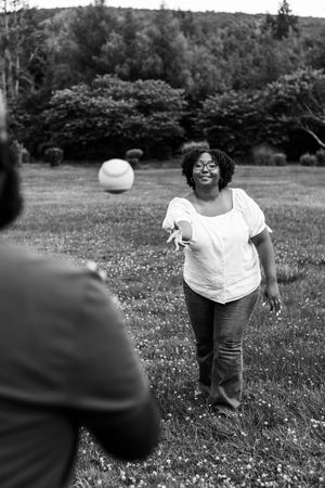 A series of black and white photos showing someone playing with a ball in a grassy field with wildflowers.